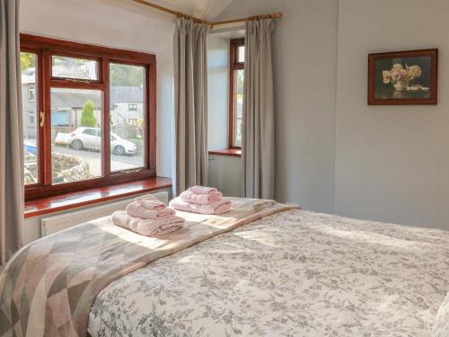 a bedroom with a bed with two pink towels on it at Lees Cottage in Bradwell