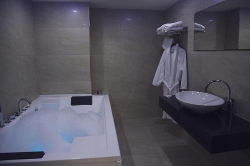 a bathroom with a bath tub and a sink at City Hotel in Prizren