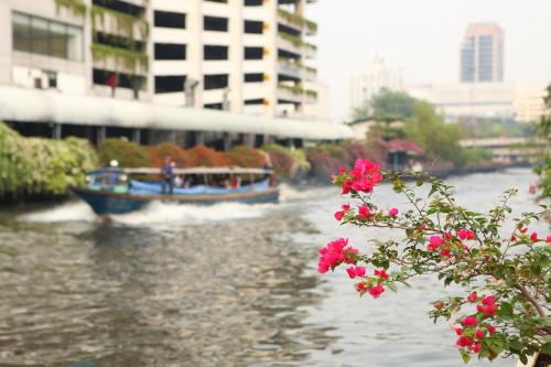 una barca che percorre un fiume con fiori rosa di Vintage Studio Apartment Thonglor Ekkamai a Ban Na Song