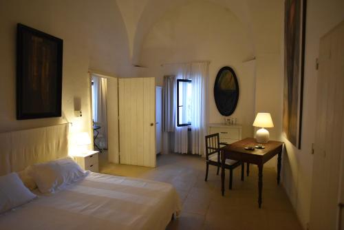 a bedroom with a bed and a desk and a table at Masseria Frassaniti by My Home Apulia in Veglie