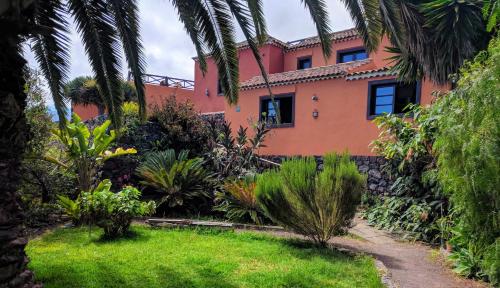 an orange house with palm trees in front of a yard at Casa Ida in Garachico