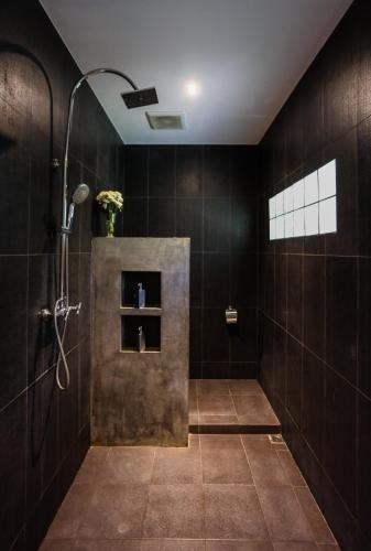 a bathroom with a shower with black tiles at Naiharn Beach Resort - SHA Plus Extra in Nai Harn Beach