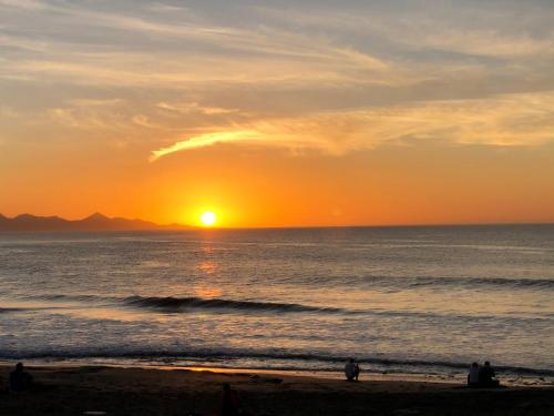 a sunset over the ocean with people on the beach at Villa Oliva Fuerteventura in Tuineje