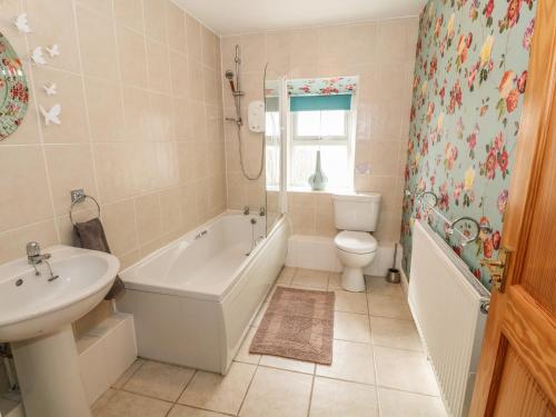 a bathroom with a tub and a toilet and a sink at Tyn Y Giat in Gaerwen