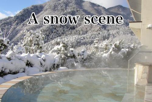 a snow scene of a swimming pool with a snow covered mountain at Hotel Miki in Gero