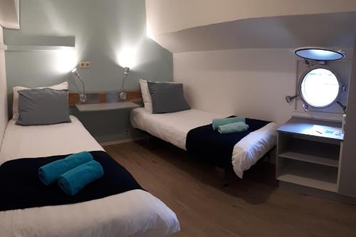een kleine kamer met 2 bedden en een raam bij Rooms on Water in Rotterdam