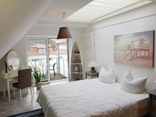 ein weißes Schlafzimmer mit einem Bett, einem Schreibtisch und einem Fenster in der Unterkunft Ostseeblick Baabe in Baabe