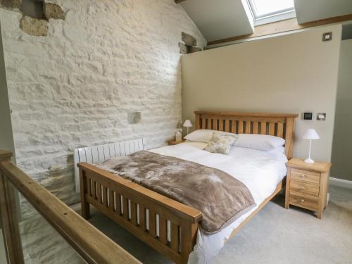a bedroom with a bed and a brick wall at Saetr Cottage in Harrop Fold