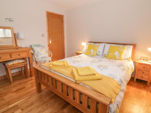 um quarto com uma cama grande com lençóis amarelos em The Stable at Church Farm House em Cantley