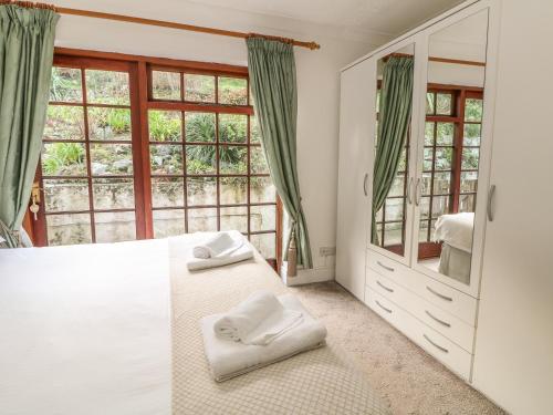 a bedroom with a white bed and a large window at Mengarth in Cadgwith