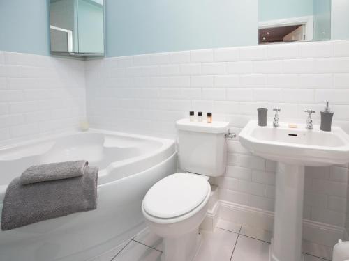 a white bathroom with a toilet and a sink at The Tynemouth Cottage in Tynemouth