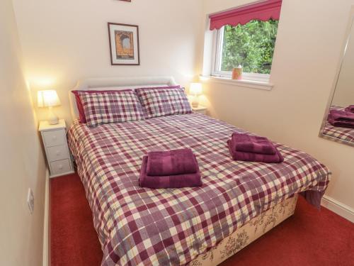 a bedroom with a bed with two purple pillows on it at Troloss Lodge in Thornhill