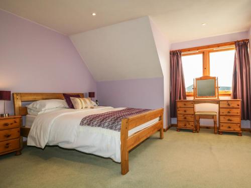 a bedroom with a bed and a desk and a television at Corriemhor Beag in Cromdale