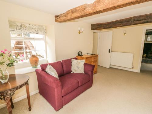 a living room with a red couch and a table at Town End Farmhouse in Newby Bridge