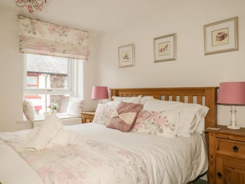 ケズウィックにあるBrigham Row Cottageのベッドルーム1室(白いシーツ付きのベッド1台、窓付)