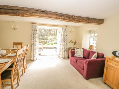 a living room with a red couch and a table at Town End Farmhouse in Newby Bridge