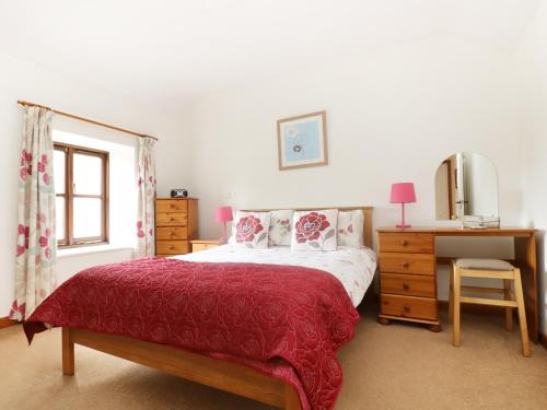 a bedroom with a bed with a red blanket and a desk at The Old Granary in Launceston