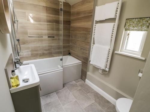 a bathroom with a tub and a toilet and a sink at Saetr Cottage in Harrop Fold