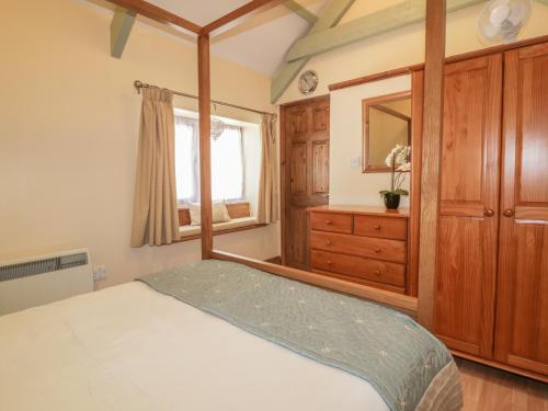 a bedroom with a bed and a dresser and a mirror at Barn Cottage in Liskeard
