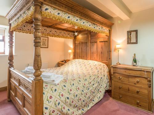 ein Schlafzimmer mit einem Himmelbett und einer Holzkommode in der Unterkunft Jenny's Cottage in Alnwick