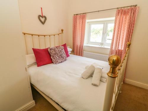 a bedroom with a bed with red pillows and a window at Woodbine Cottage in Ambleside