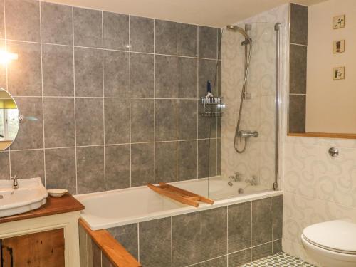 a bathroom with a tub and a toilet and a sink at Beck Cottage in Ulverston