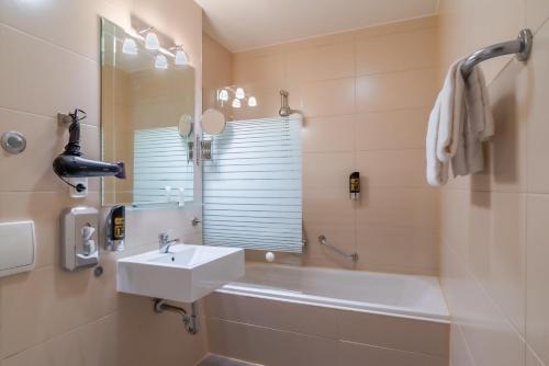 a bathroom with a sink and a tub and a mirror at Hotel Astor in Munich