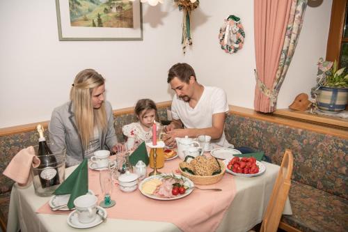 a family sitting at a table eating food at Appartement-Pension Fahrnberggut in Rauris