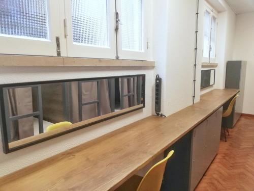 a long wooden counter in a room with windows at Draft Hostel & Rooms in Lisbon