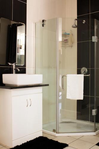 a bathroom with a sink and a glass shower at Sarah's Place Guesthouse in Pretoria