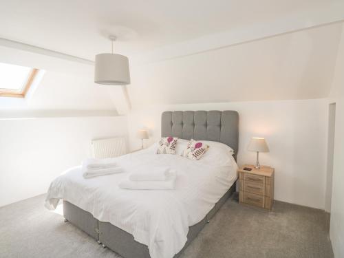 1 dormitorio con 1 cama grande con sábanas y almohadas blancas en Lower West Curry Cottage, en Launceston
