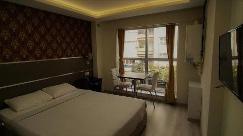 a bedroom with a bed and a table and a window at Aydın Kent Suit in Aydın
