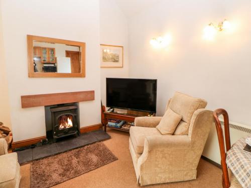 a living room with a fireplace and a television at The Byre in Brampton