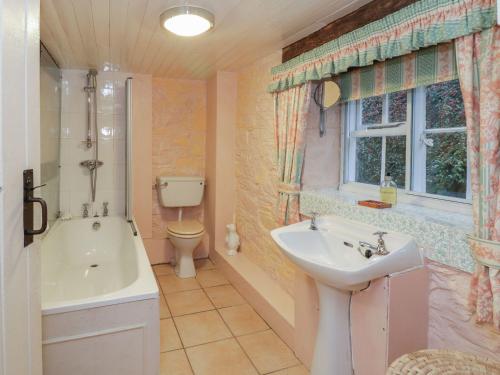 La salle de bains est pourvue d'une baignoire, d'un lavabo et de toilettes. dans l'établissement Dolgenau Cottages, à Trefeglwys