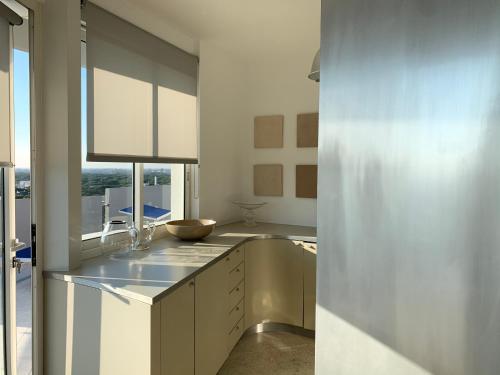 a kitchen with white cabinets and a large window at Penthouse Bellavista in Lignano Sabbiadoro