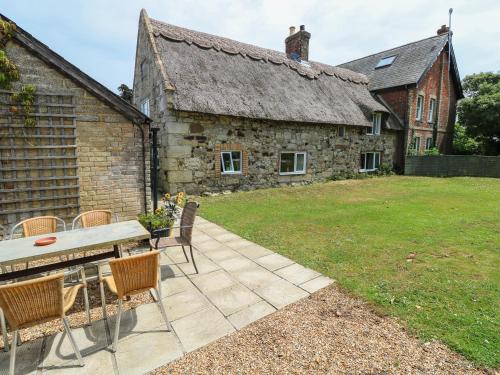 a patio with chairs and a table in front of a building at Hill Farm Cottage in Freshwater