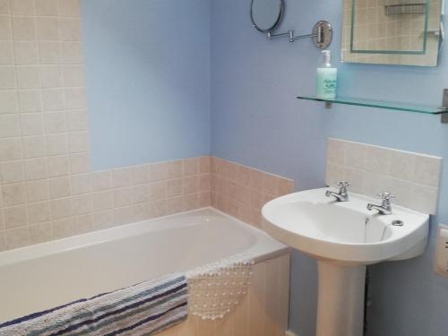 a bathroom with a sink and a bath tub and a sink at Rose Cottage in Chard
