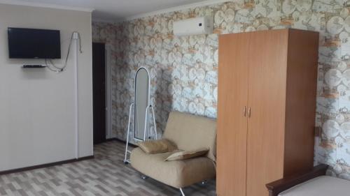 Habitación con silla, TV y armario. en Гостевой дом Сафар, номера с отдельным входом, en Kapchagay