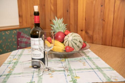 a bottle of wine and a bowl of fruit on a table at Appartement-Pension Fahrnberggut in Rauris
