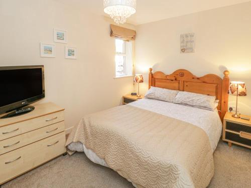 a bedroom with a bed and a flat screen tv at Beach View in Benllech