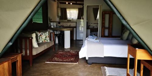 a small bedroom with a bed and a kitchen at Kingfisher Bush Lodge in Enkovukeni