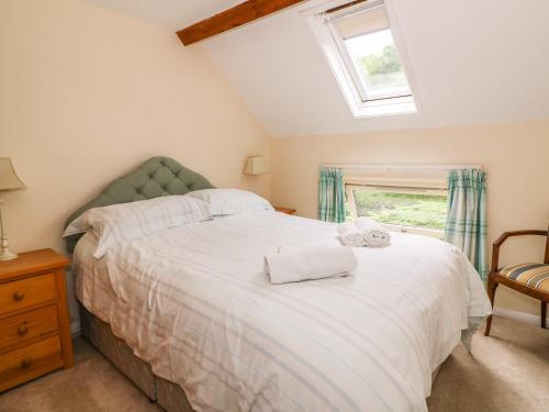 a bedroom with a large white bed with a window at Gardener's Cottage in Llandrindod Wells