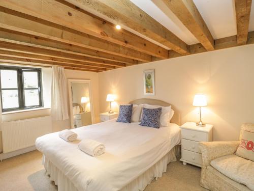 a bedroom with a large white bed and a chair at The Barn in Shaftesbury