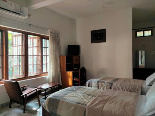 Un dormitorio con dos camas y un escritorio y una ventana. en Anashwara, en Kozhikode