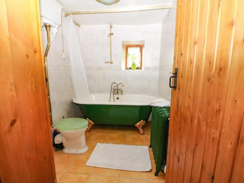 a bathroom with a green tub and a toilet at Brook Cottage in Hayfield
