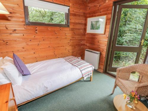 a bedroom in a log cabin with a bed and a chair at Buttermere in Ulverston