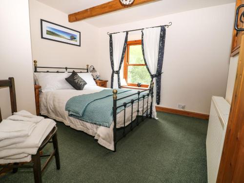 a bedroom with a bed and a window at Brook Cottage in Hayfield