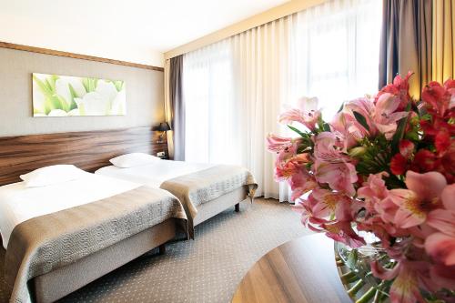 una habitación de hotel con 2 camas y un jarrón de flores en Golden Tulip Krakow City Center, en Cracovia
