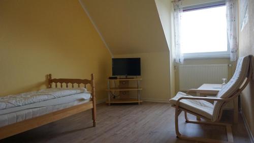 a bedroom with a bed and a tv and a chair at Logia Hotel garni in Neuharlingersiel