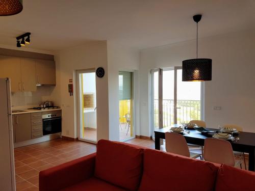 ein Wohnzimmer mit einem roten Sofa und einem Tisch in der Unterkunft Cozy apartment in Algarve West Coast - Aljezur (2 min da Praia Monte Clérigo) in Aljezur